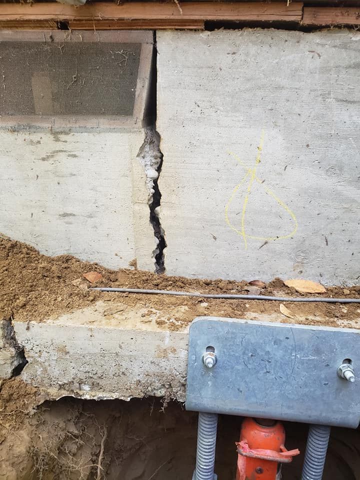 Professional retaining wall repair crew stabilizing a leaning stone retaining wall in Medford Oregon residential backyard
