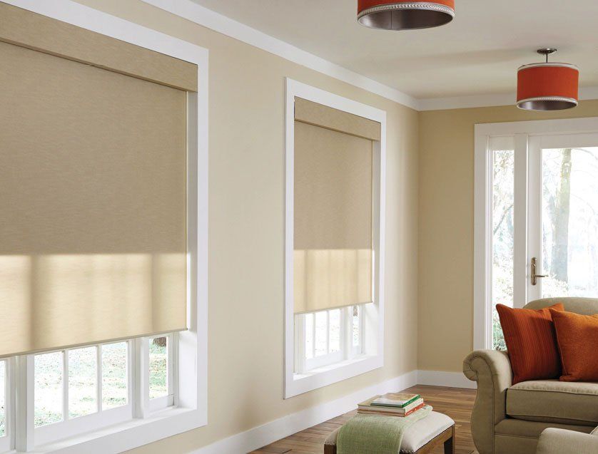 a living room with two windows that have motorized blinds