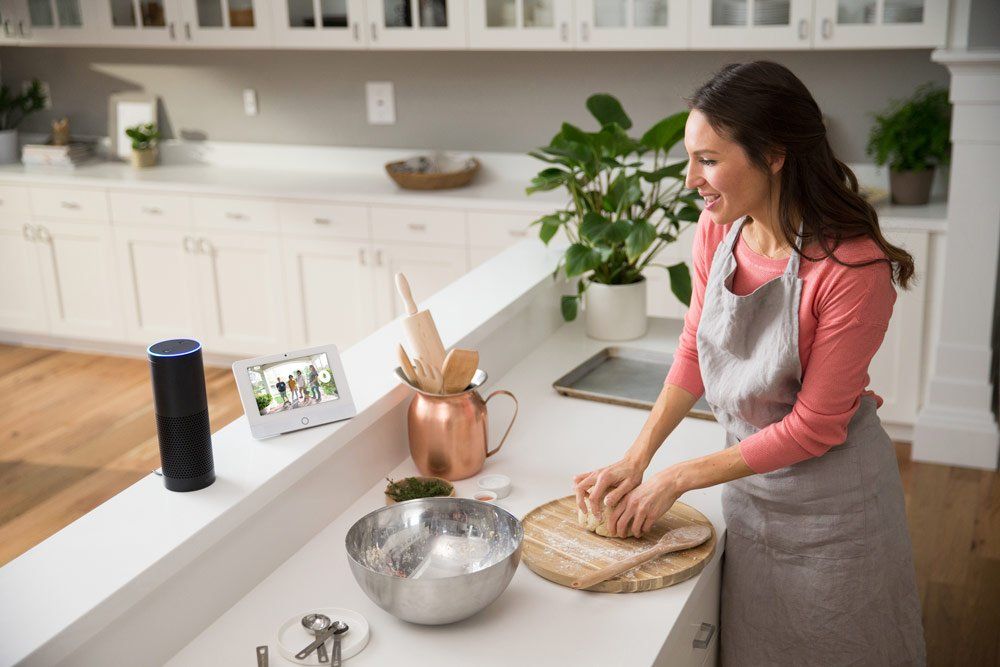 a woman kneading dough in a kitchen with an amazon echo on the counter