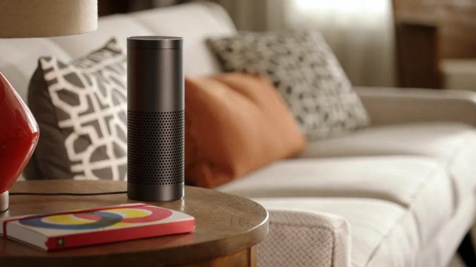 an amazon echo speaker is sitting on a table in front of a couch .