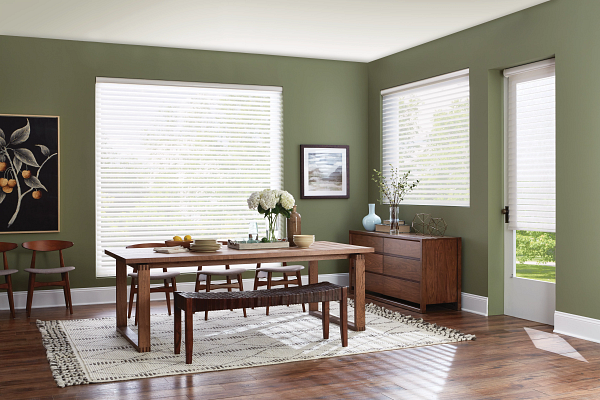 A dining room with a wooden table and chairs and green walls.