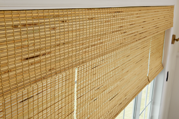 A close up of a bamboo blind on a window.