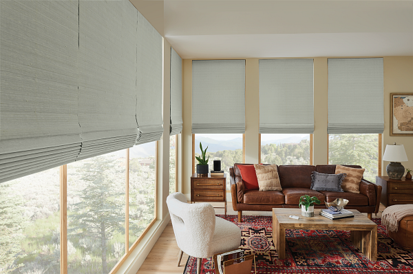 A living room with a couch , chair , coffee table and lots of windows.