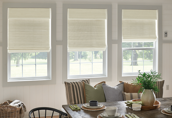 A dining room with a table and chairs and roman shades on the windows.