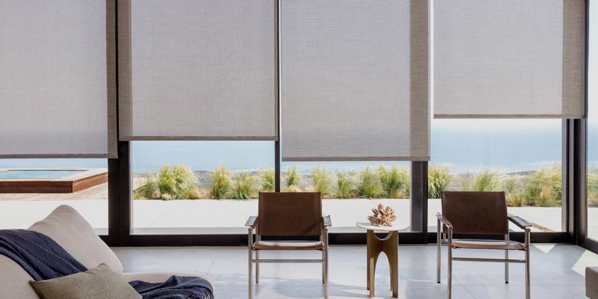 A living room with a couch , chairs and a table with a view of the ocean.