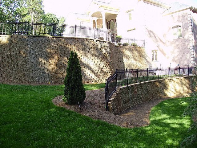 A large house with a stone wall and stairs in front of it.