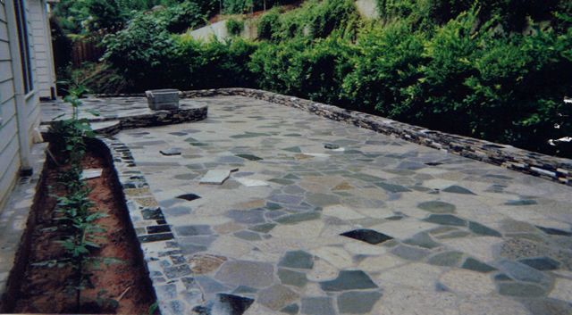 A stone walkway is being built in the backyard of a house.
