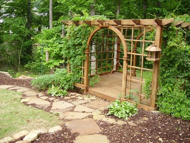 A wooden pergola with a bird feeder attached to it