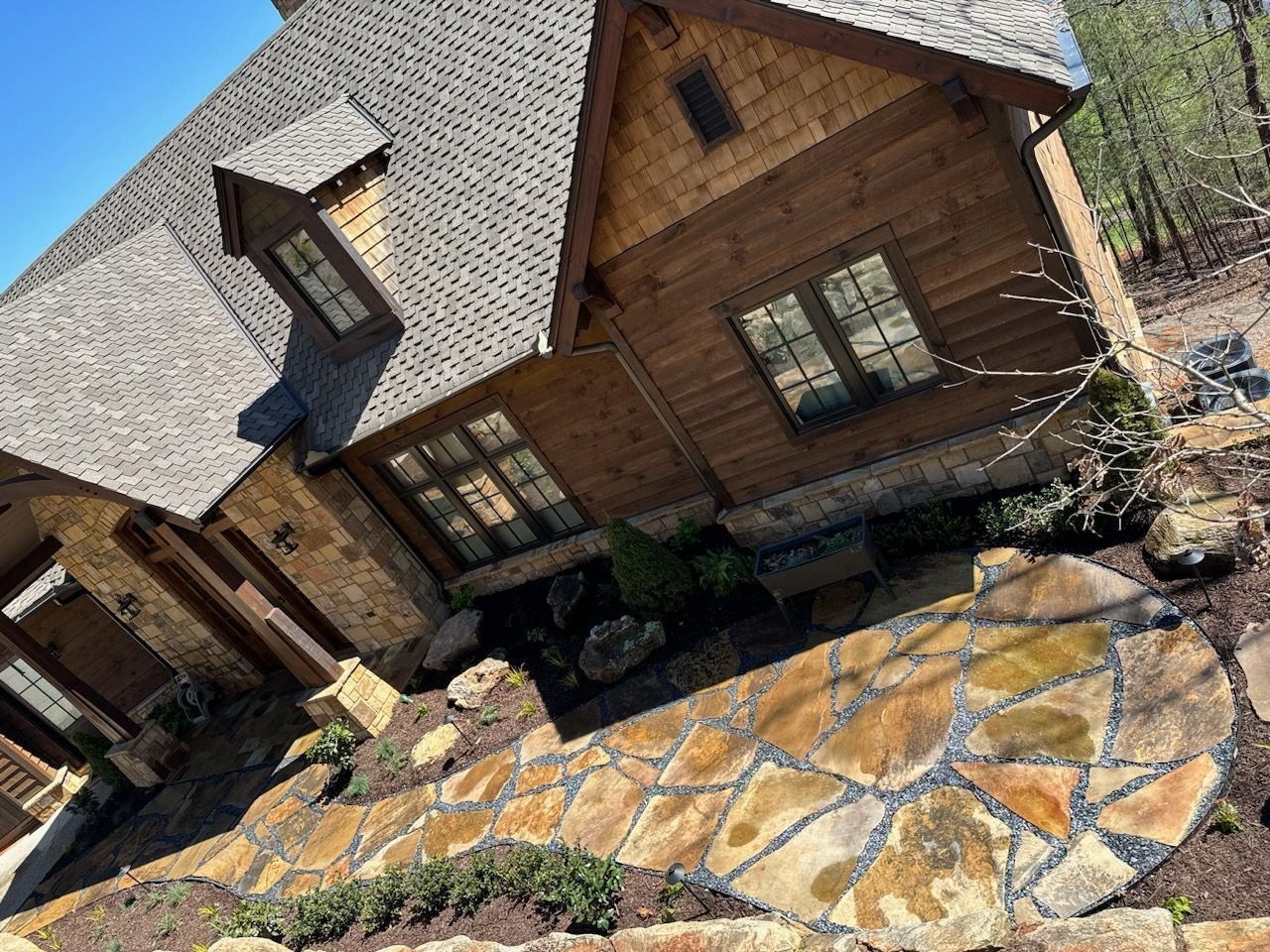 A large wooden house with a stone walkway in front of it.