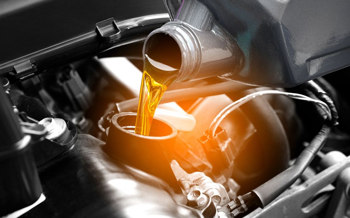 Motor oil being poured into a car engine's oil fill hole; close-up.