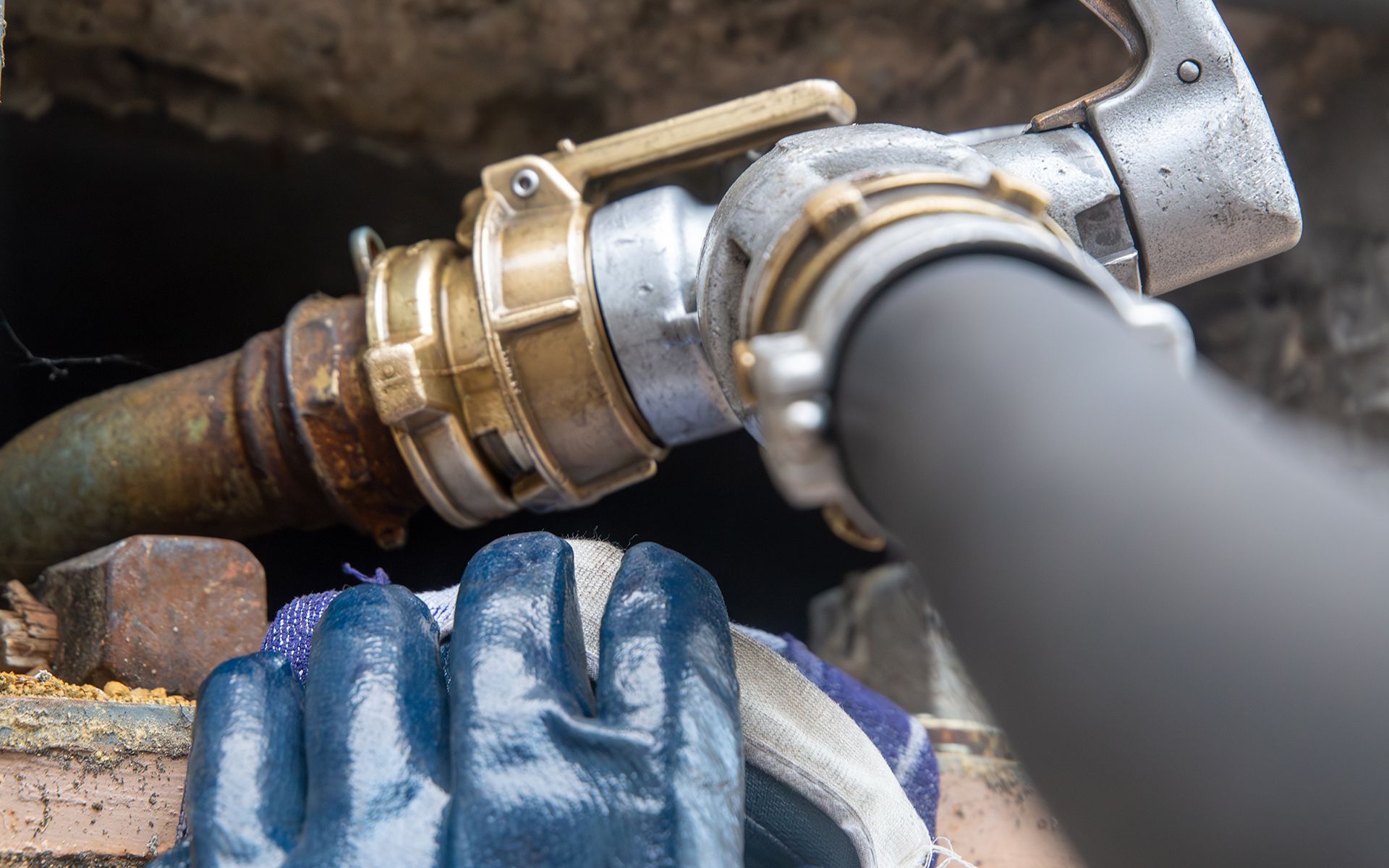 Hose connection with silver and brass parts; a gloved hand underneath.