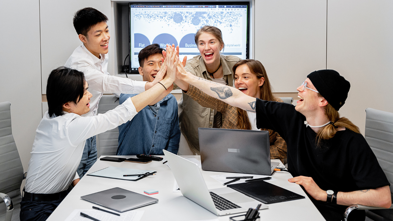 A group of people are giving each other a high five in a conference room after a corporate activity.