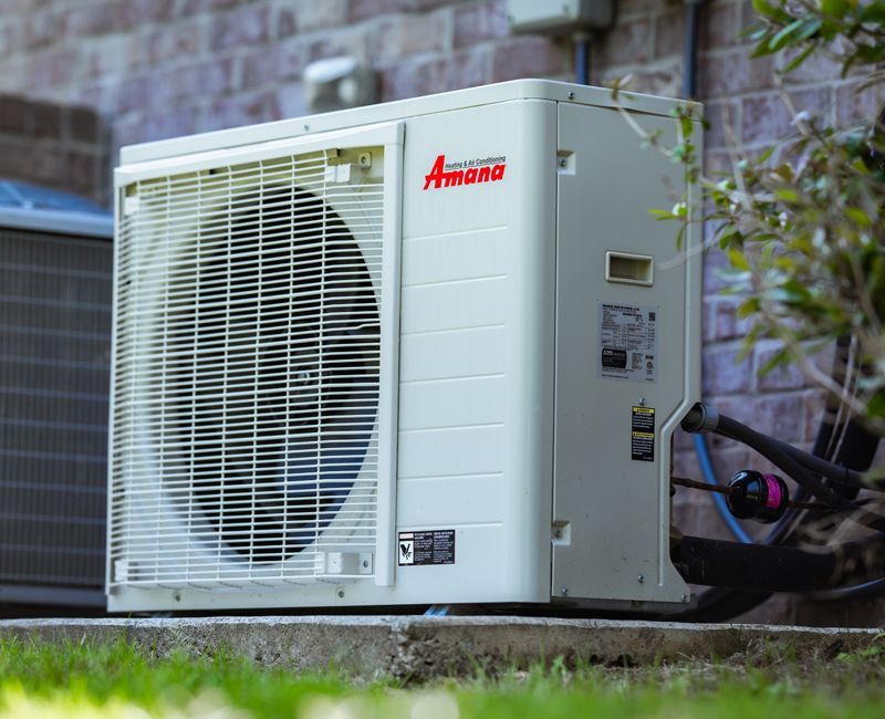 A white air conditioner is mounted on a white brick wall next to a remote control.