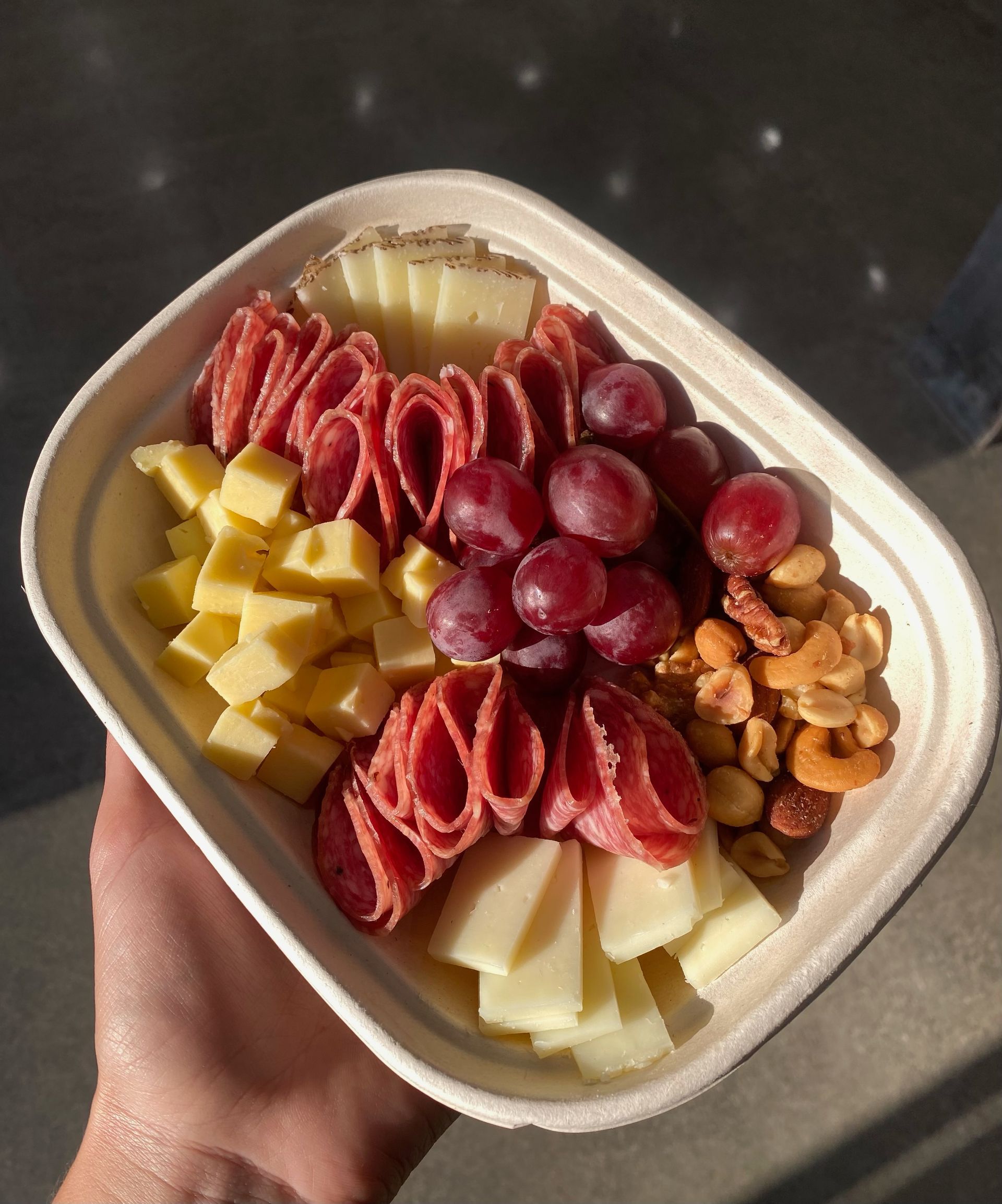 Small charcuterie box with an assortment of meats, cheeses, and crackers.