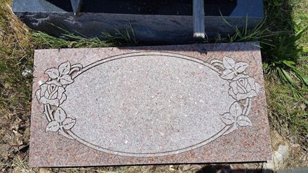 a gravestone with a floral design on it is in a graveyard .
