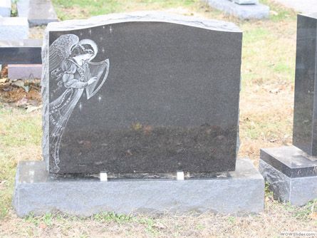 a black gravestone with an angel on it is in a cemetery .