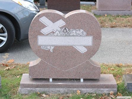 a gravestone in the shape of a heart with a cross on it