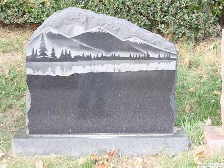 a gravestone with a mountain and trees on it