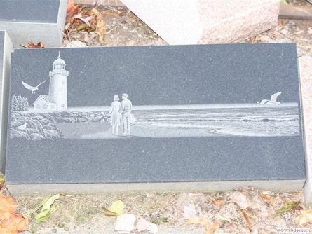 a gravestone with a lighthouse and a couple on it