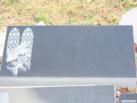 a black gravestone with a picture of a stained glass window on it .