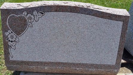 a gravestone with a heart and flowers on it .