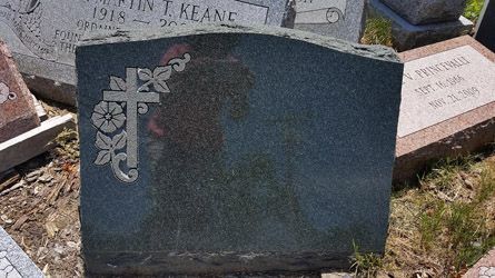 a gravestone in a cemetery with a cross and flowers on it .