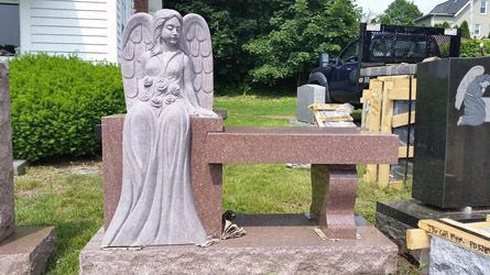 a statue of an angel sitting on a bench in a cemetery .