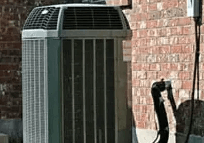 An air conditioner is sitting on the side of a brick building.
