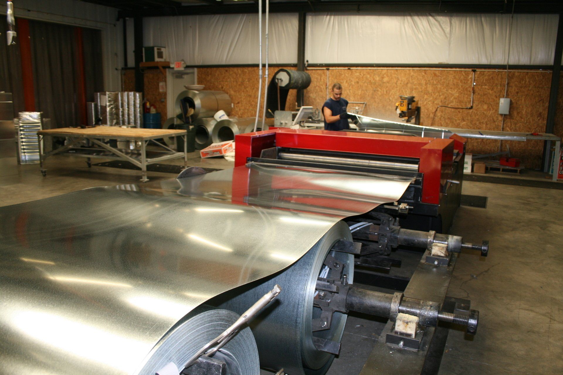 A man is standing in front of a machine that is cutting a piece of metal.