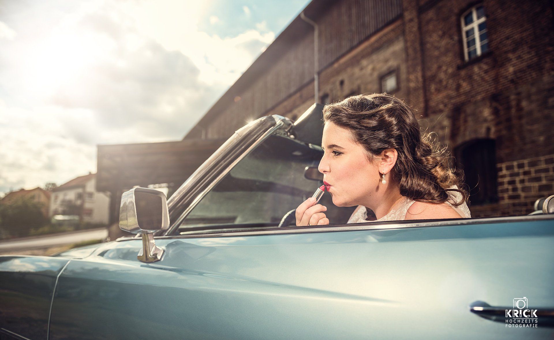 Eine Frau trägt in einem Cabrio Lippenstift auf.