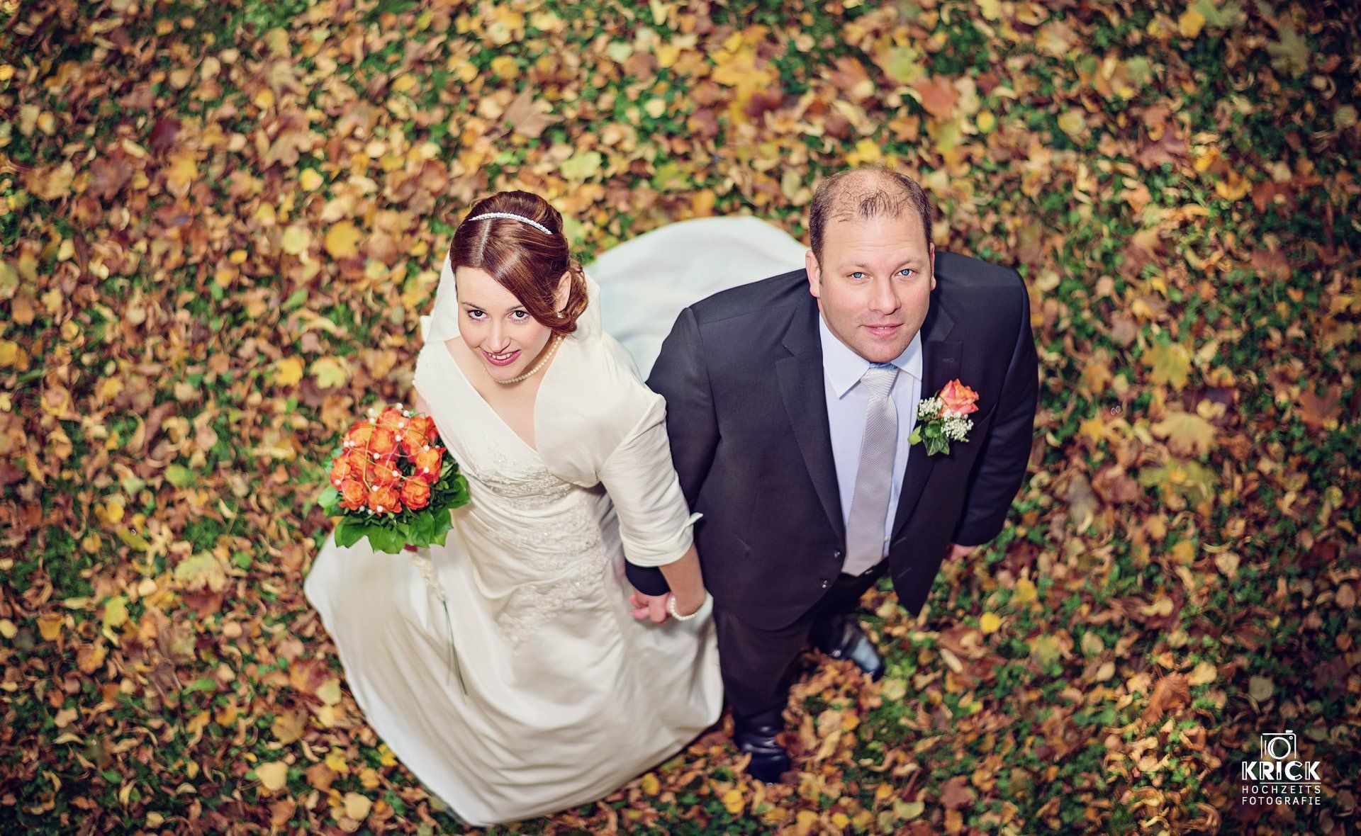 Eine Braut und ein Bräutigam stehen in einem Blätterhaufen.