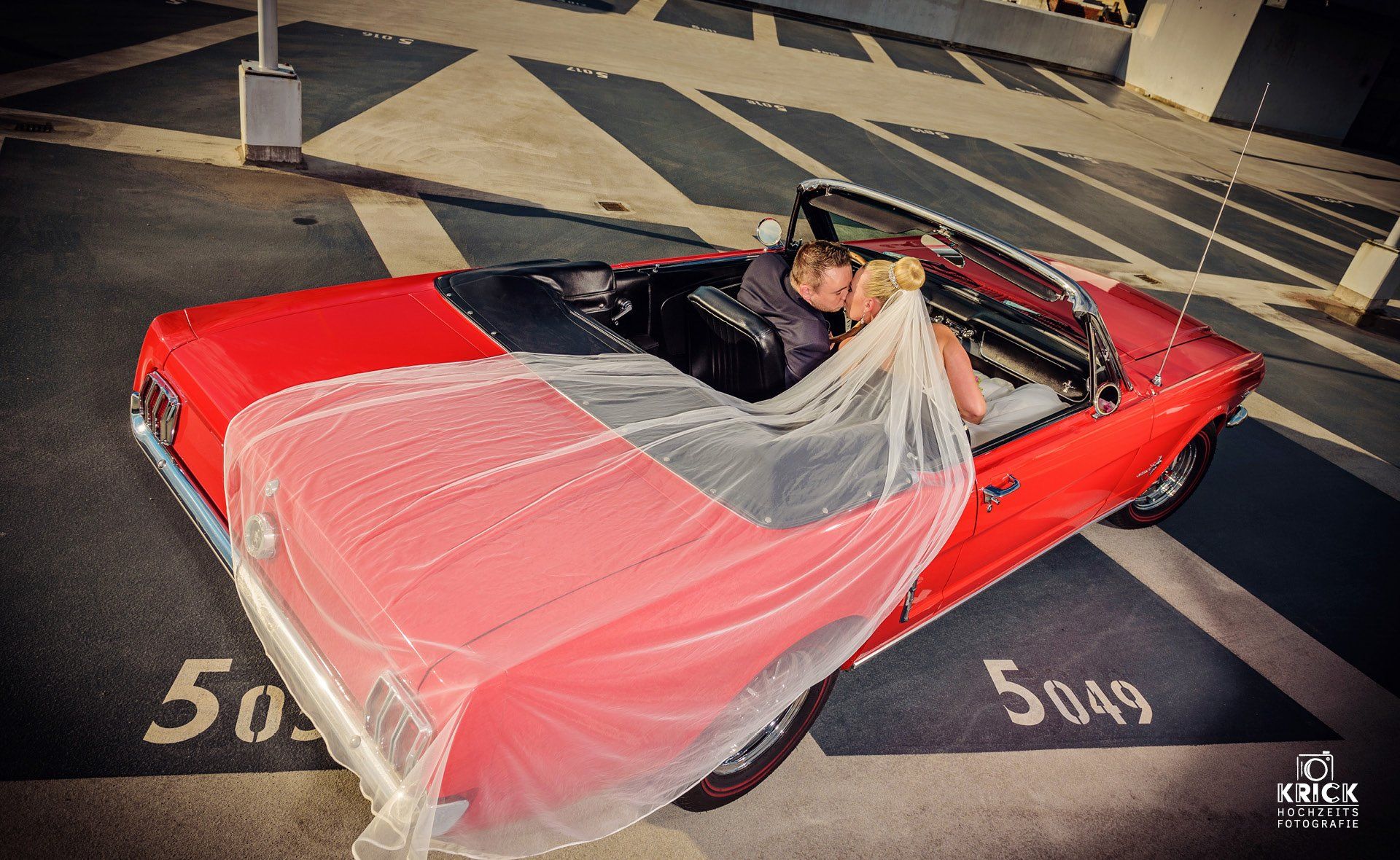 Eine Frau mit Schleier sitzt in einem roten Auto