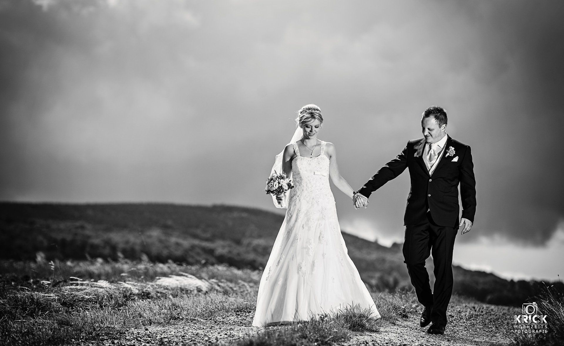 Ein Schwarzweißfoto von Braut und Bräutigam, die Händchen halten.