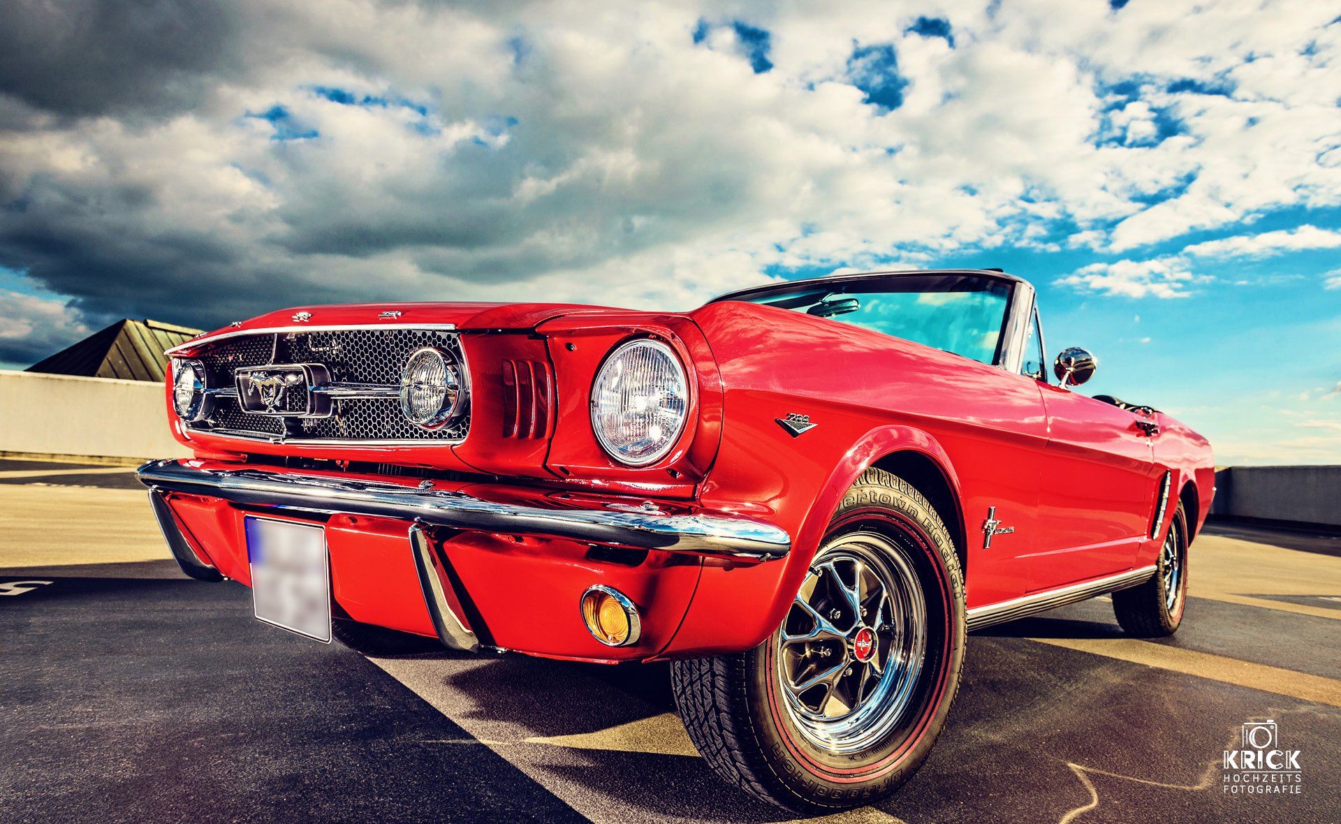 Auf einem Parkplatz steht ein rotes Mustang Cabrio.