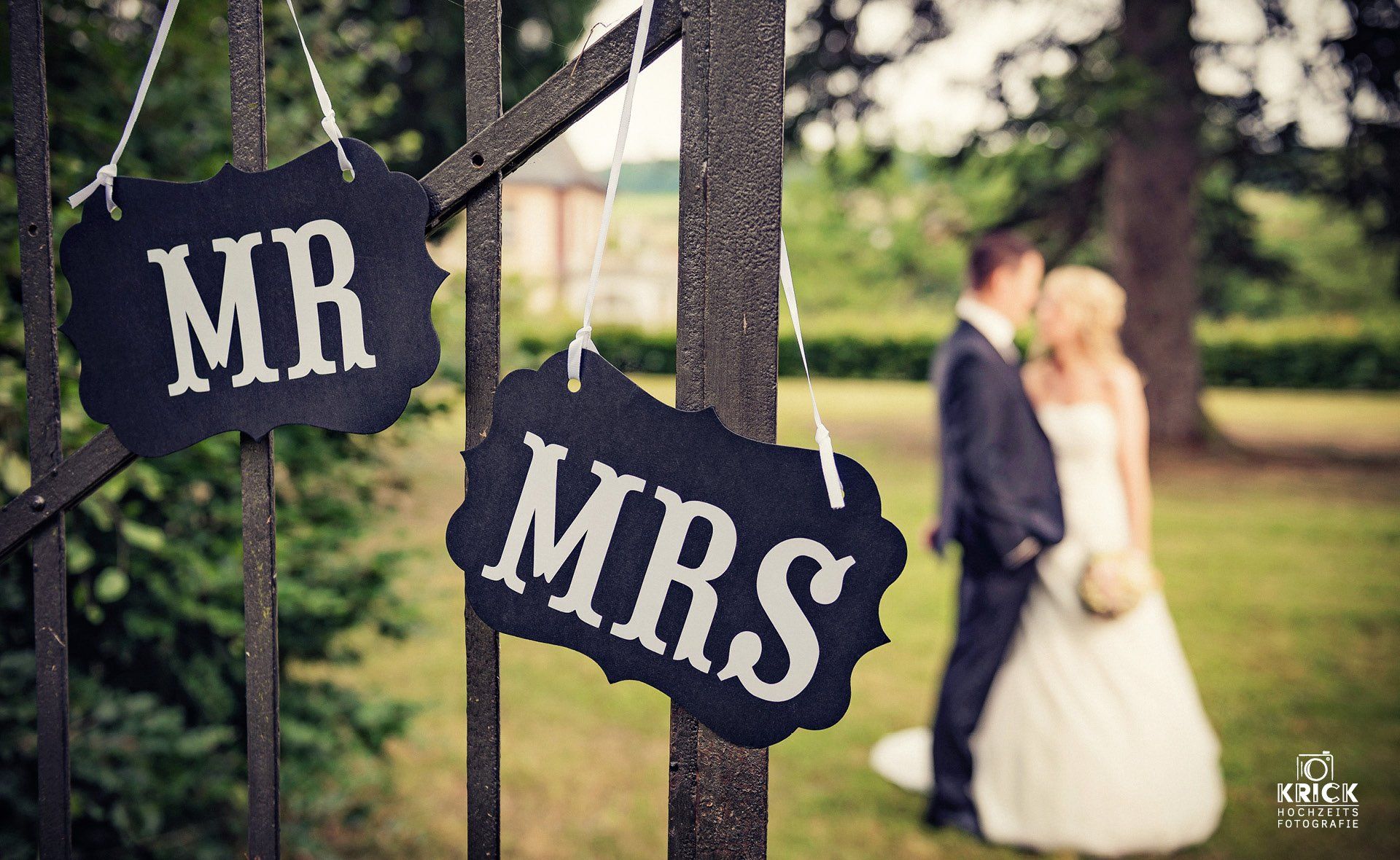 Braut und Bräutigam küssen sich hinter Schildern mit der Aufschrift „Mr. und Mrs.“