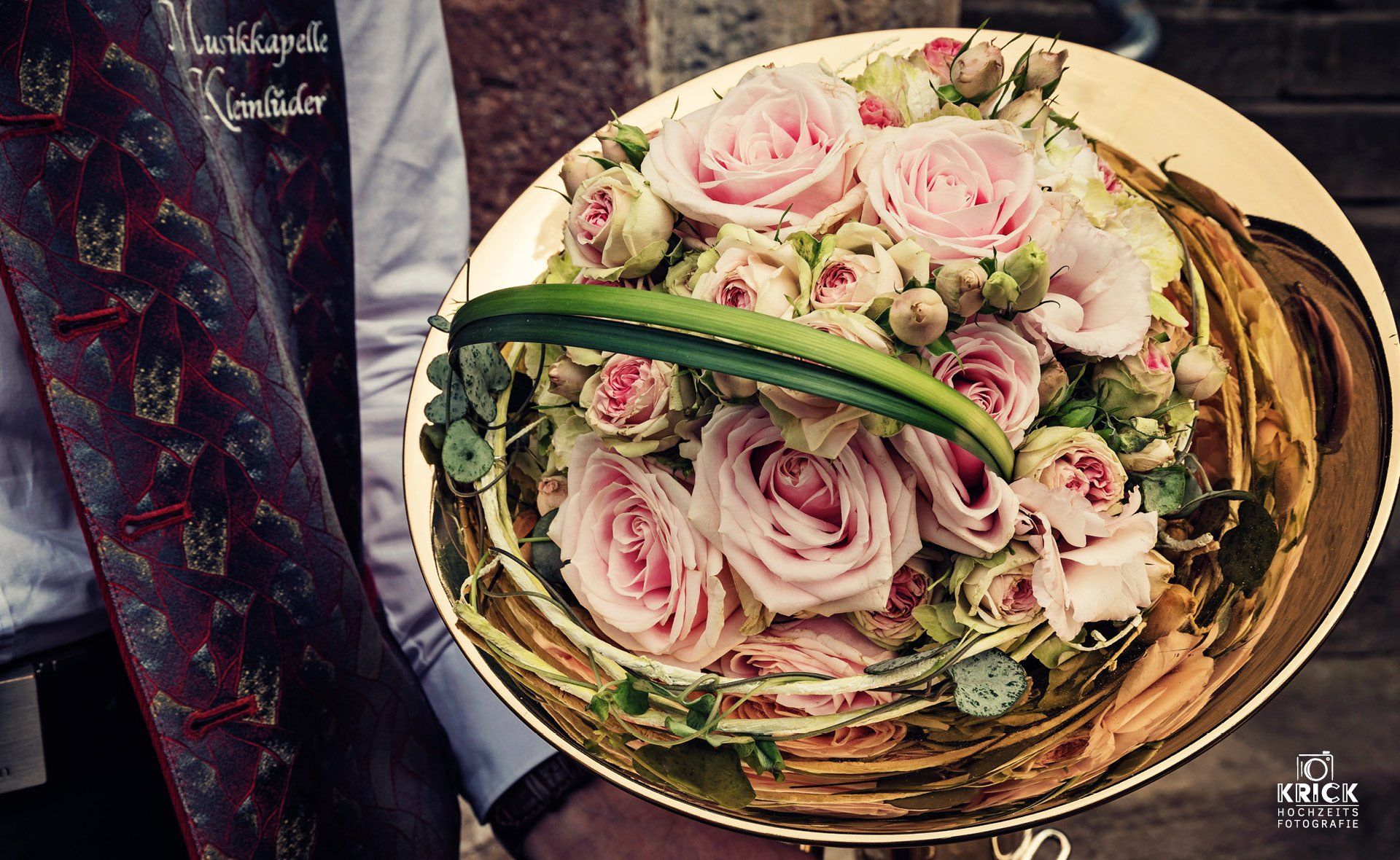 Eine Person hält einen goldenen Teller mit rosa Rosen darauf