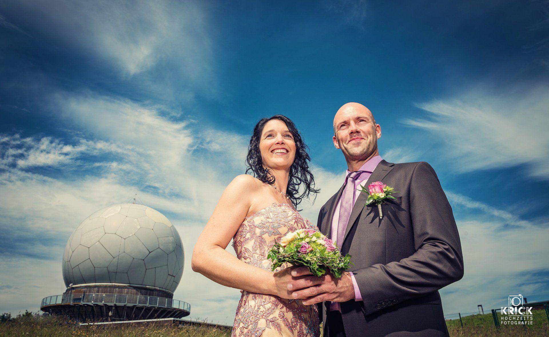 Eine Braut und ein Bräutigam posieren für ein Foto vor einer großen Kuppel.