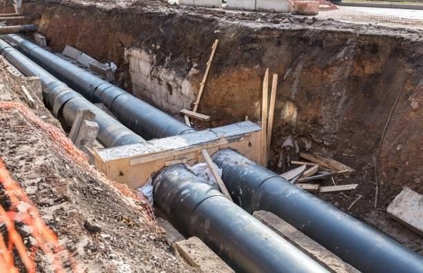 A bunch of pipes are being installed in a trench.