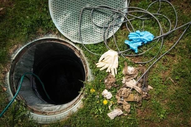 A manhole cover with a hose , gloves , and a hose coming out of it.