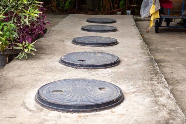 A row of manhole covers on a concrete walkway.