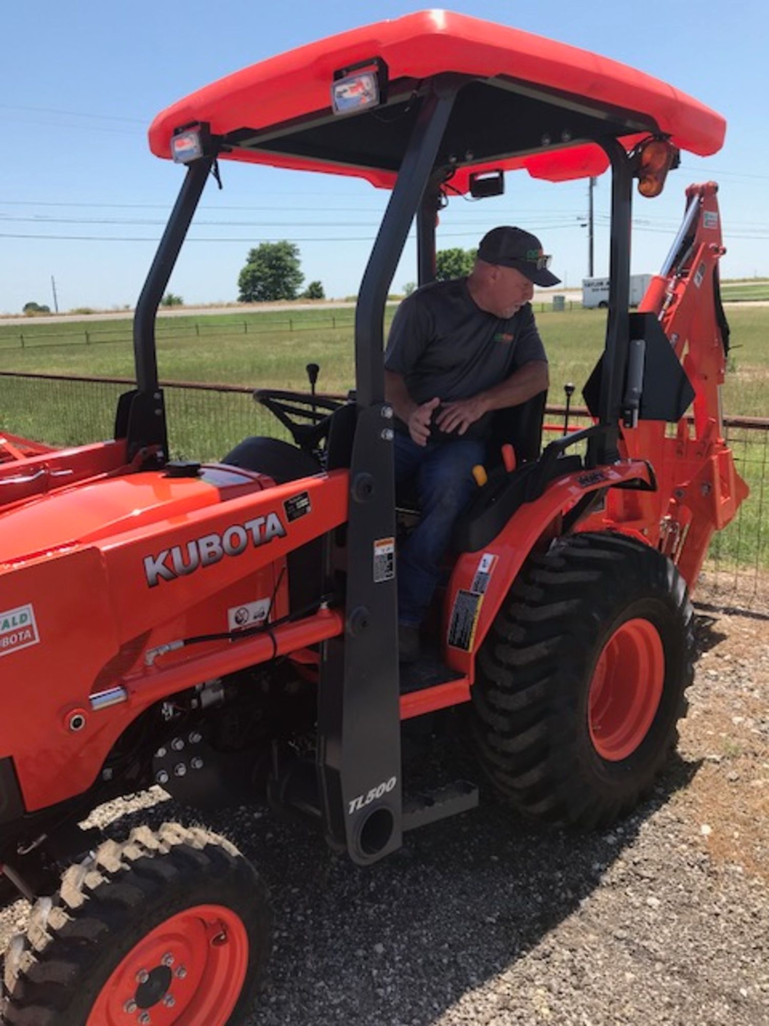 A man is sitting in the driver 's seat of a kubota tractor.