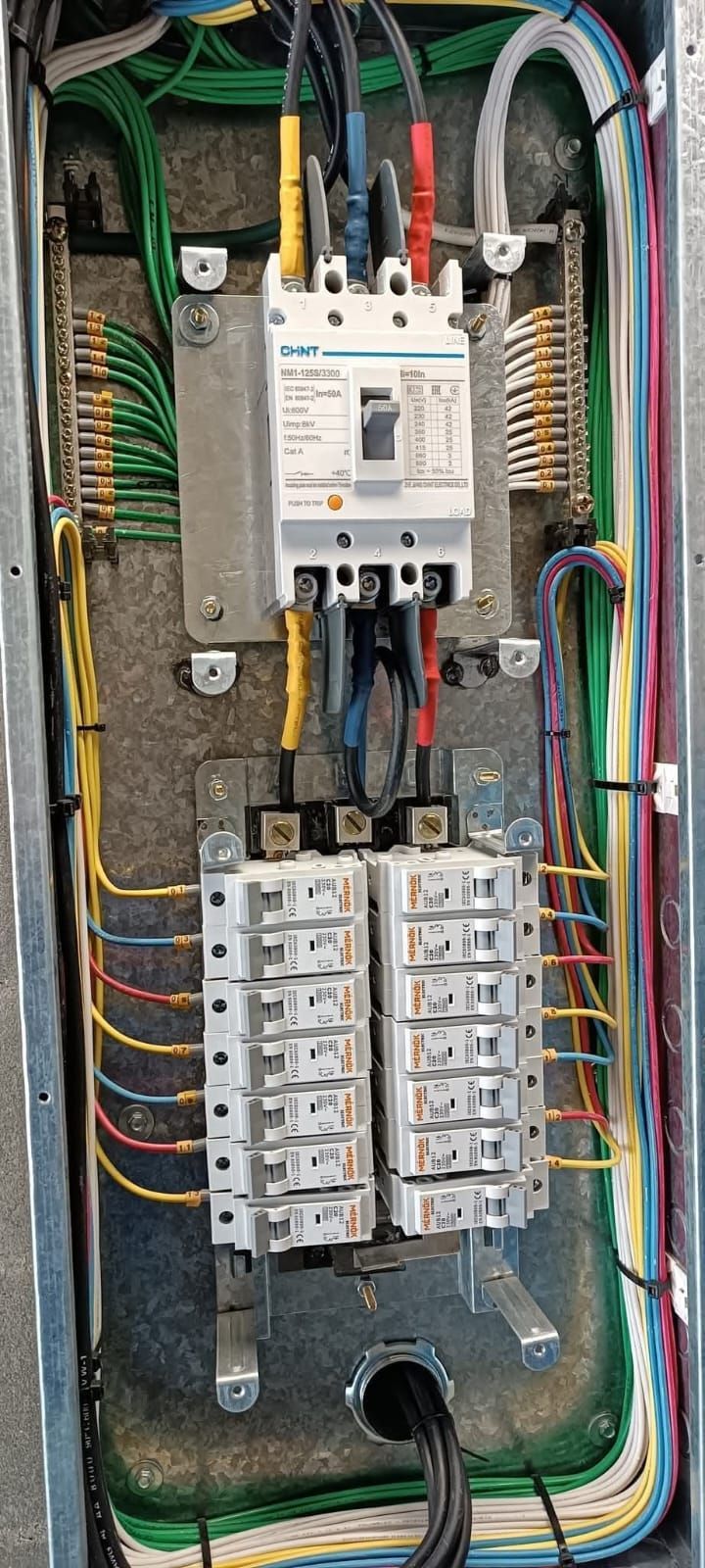 Panel eléctrico con cables de varios colores conectados a disyuntores y terminales.