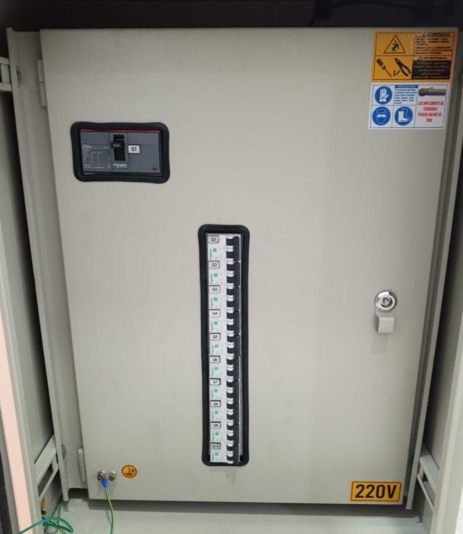 Panel eléctrico de tono neutro con disyuntor, indicador de nivel de líquido y etiquetas de seguridad. La etiqueta 