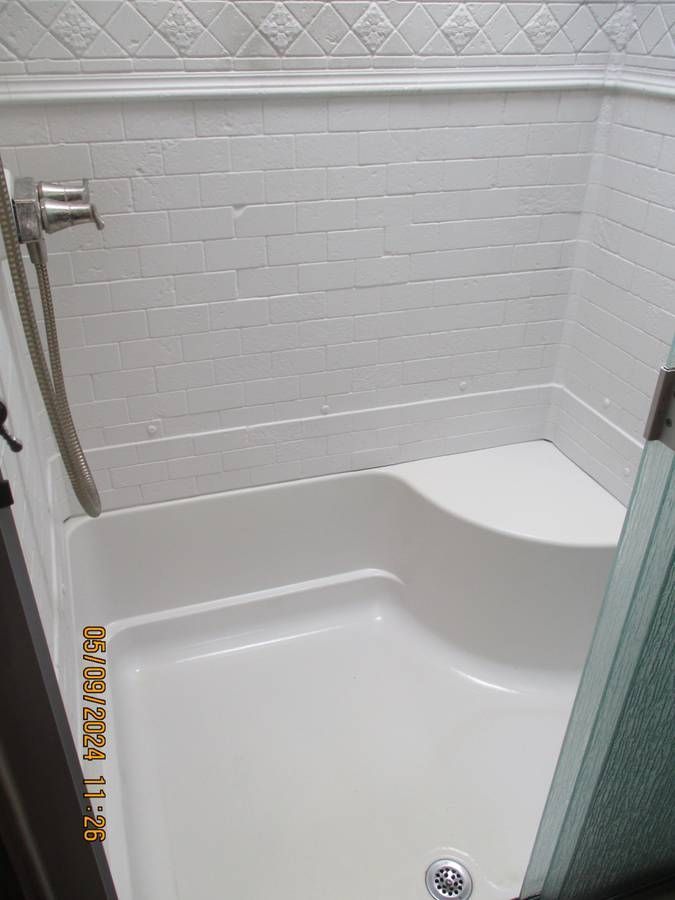 A shower stall with a seat and a shower head in a bathroom.