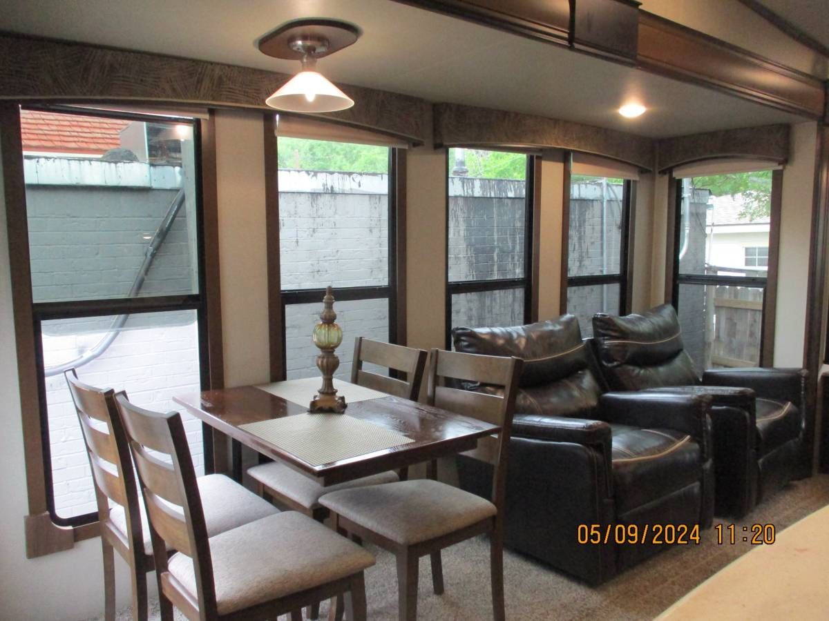 A living room with a table and chairs and a lot of windows