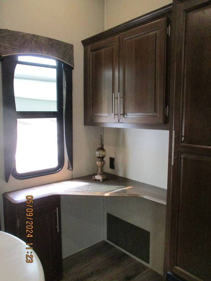 A corner of a room with wooden cabinets and a window.