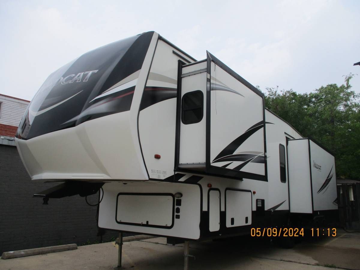 A white and black rv is parked in a parking lot.