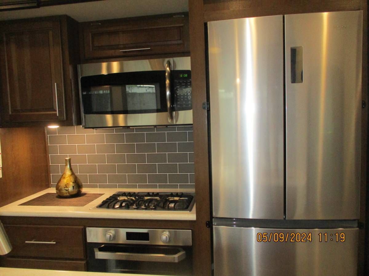 A kitchen with stainless steel appliances including a refrigerator and microwave