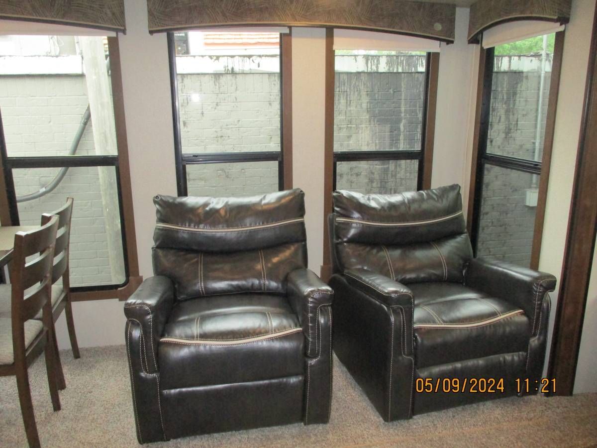 Two black leather recliner chairs are sitting next to each other in a living room.
