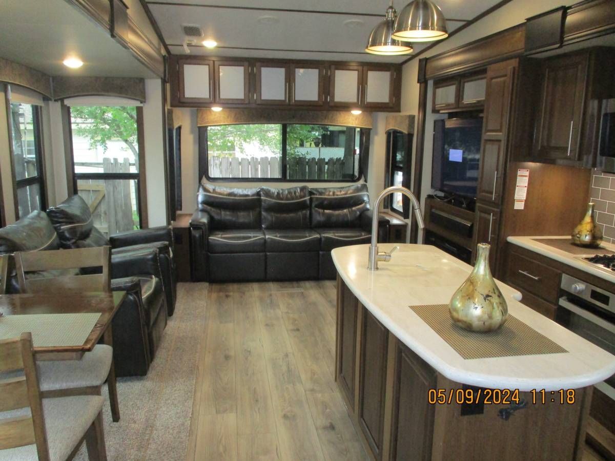 A rv with a living room , dining room , and kitchen.